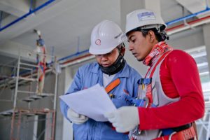 Construction workers wearing safety helmets reviewing documents at an active job site